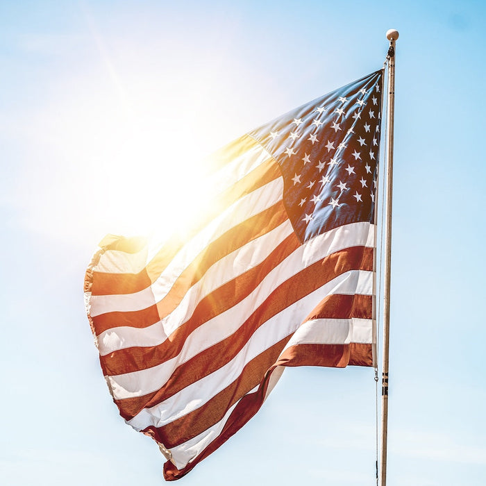 United States flag on a flag pole with the sun shining