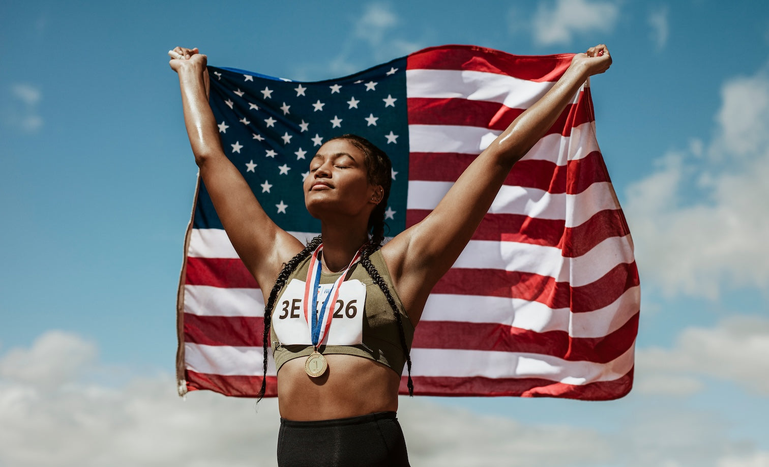 woman athlete with medal raising an American Flag