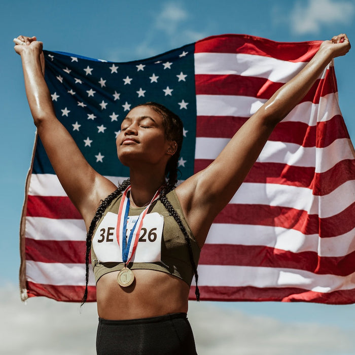 woman athlete with medal raising an American Flag