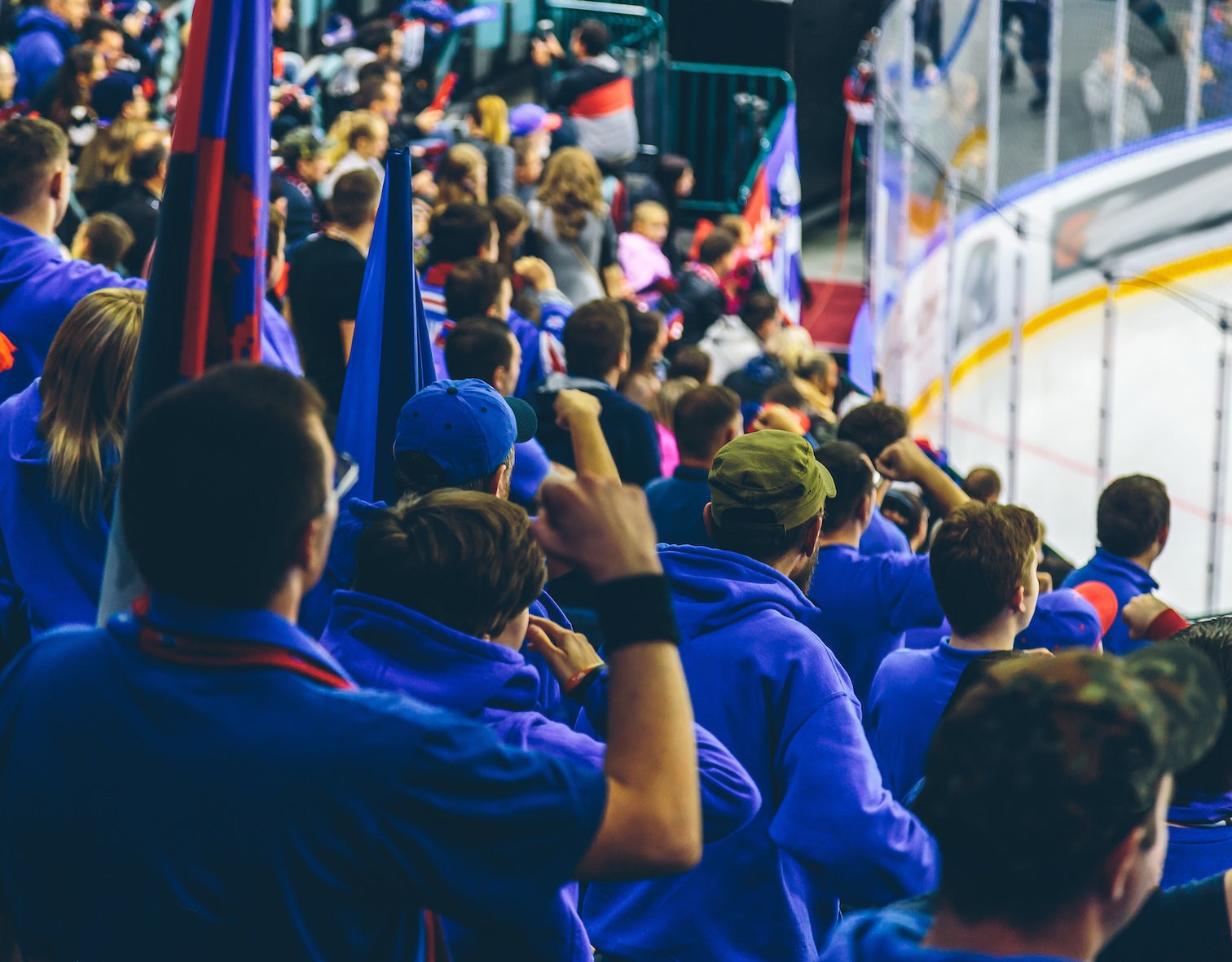 hockey fans sitting in stadium holding flags and wearing blue shirts