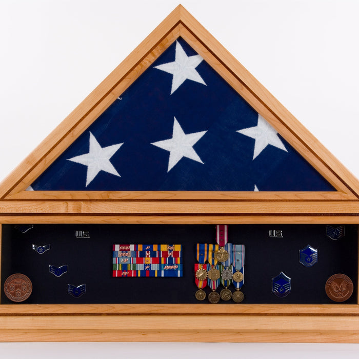 shadow box filled with a triangle folded American flag on top of military medals and pins