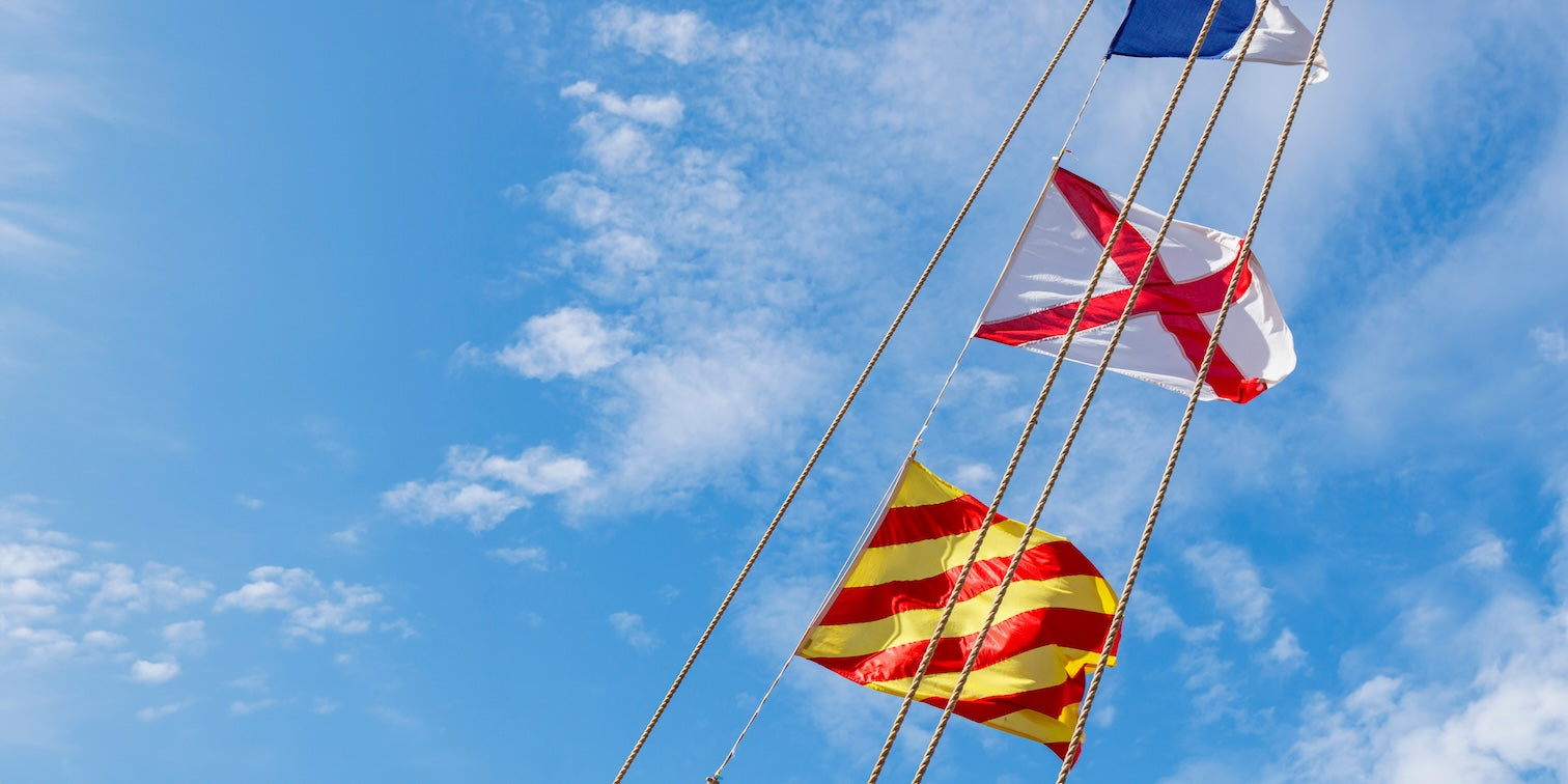 3 nautical marine flags hanging on stretched cable lines with blue sky background