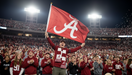 Person holding a red flag with a white letter 'A' in a stadium filled with fans.
