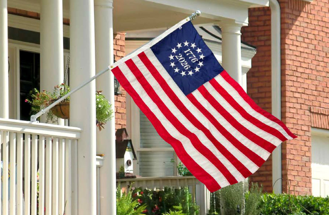 American flag on a flagpole in front of a house with a porch.