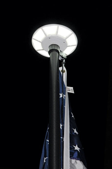 Solar powered flagpole light illuminated
