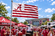 A flag featuring red and white horizontal stripes with the Alabama Crimson Tide logo in the corner.